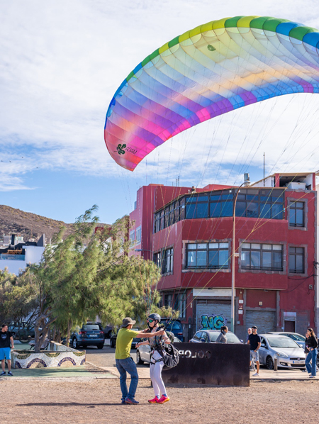 El instructor asistiendo a un alumno durante una sesión de control de suelo en Las Coloradas, Gran Canaria. El alumno está practicando las técnicas de manejo del parapente en el suelo bajo la supervisión del instructor, mientras el viento y el paisaje canario acompañan la práctica.